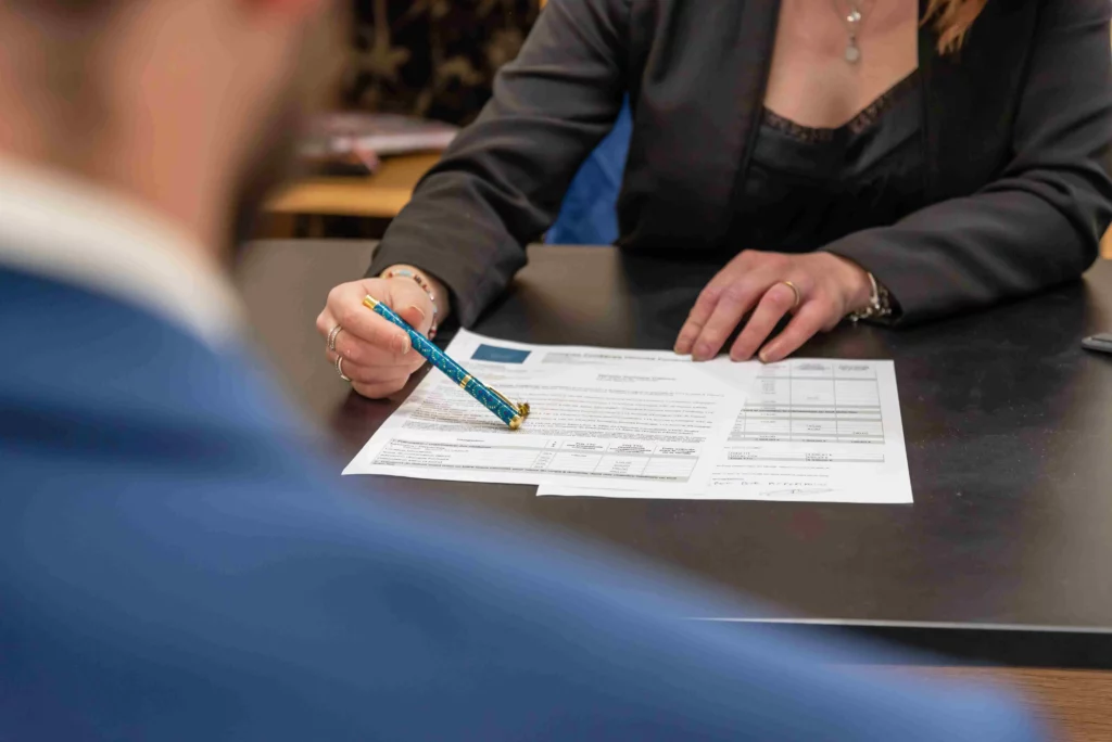 Personne en train de rédiger et signer des formalités administratives sur un bureau.