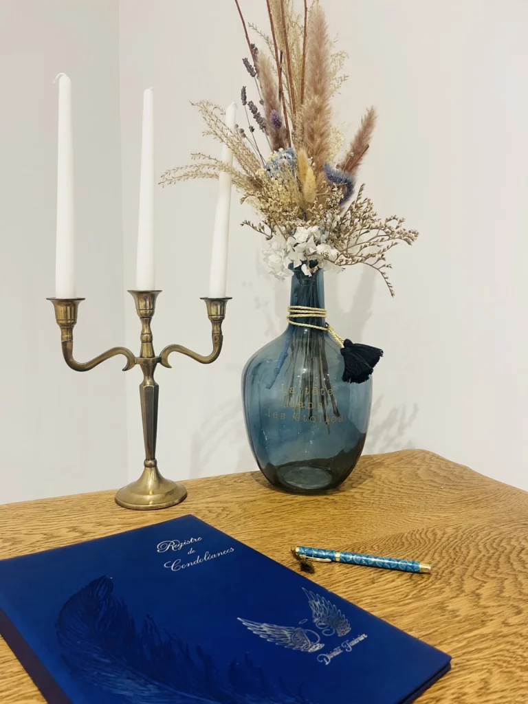 Espace hommages avec bougeoir doré, fleurs séchées et livre de condoléances
